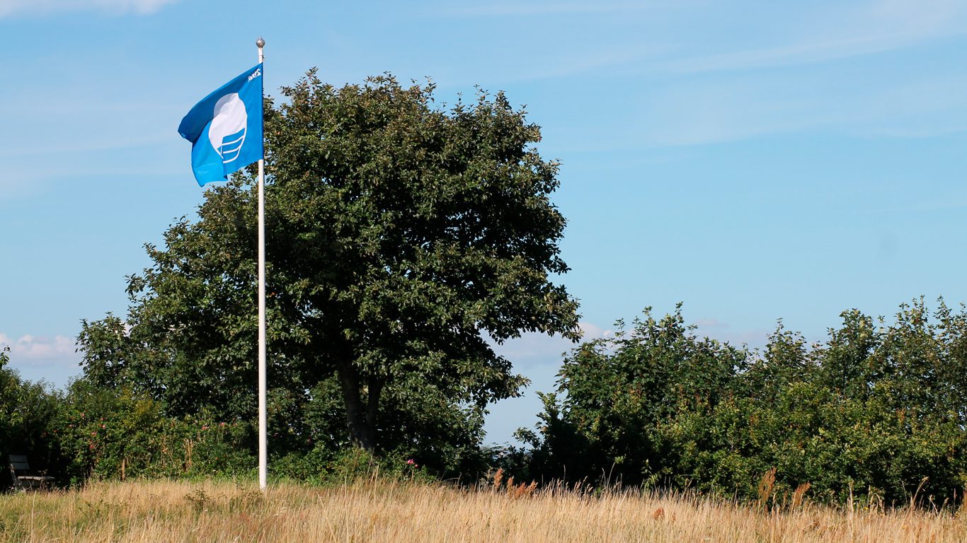 Badestrand ved Saksild med blåt flag, der indikerer høj vandkvalitet.
