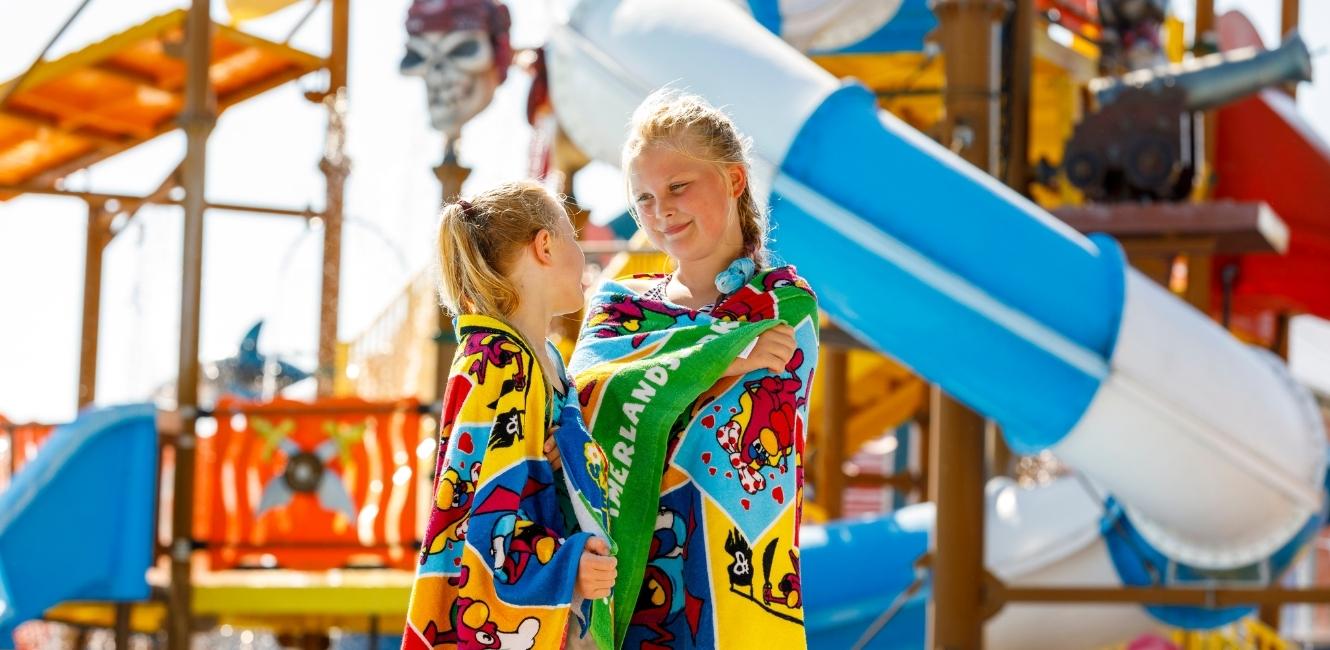 Glade børn leger i et pulserende vandland, der repræsenterer de sjove og familievenlige oplevelser i Sommerland Sjælland, en nøgleattraktion i området.
