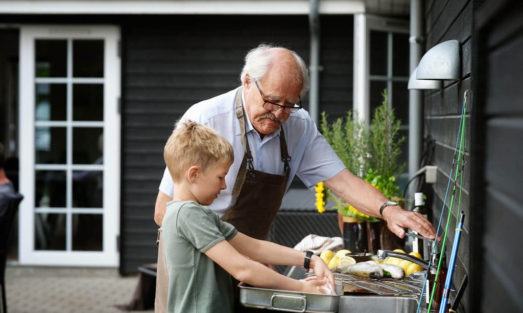 Bedstefar og barnebarn tilberede fisk i sommerhusets udekøkken