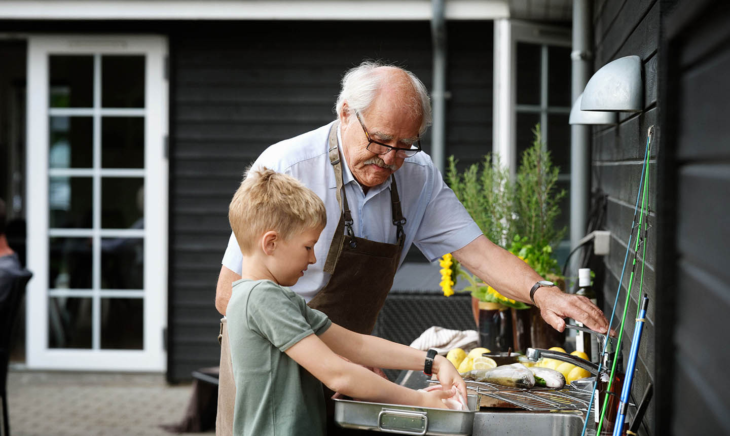 Bedstefar og barnebarn tilberede fisk i sommerhusets udekøkken