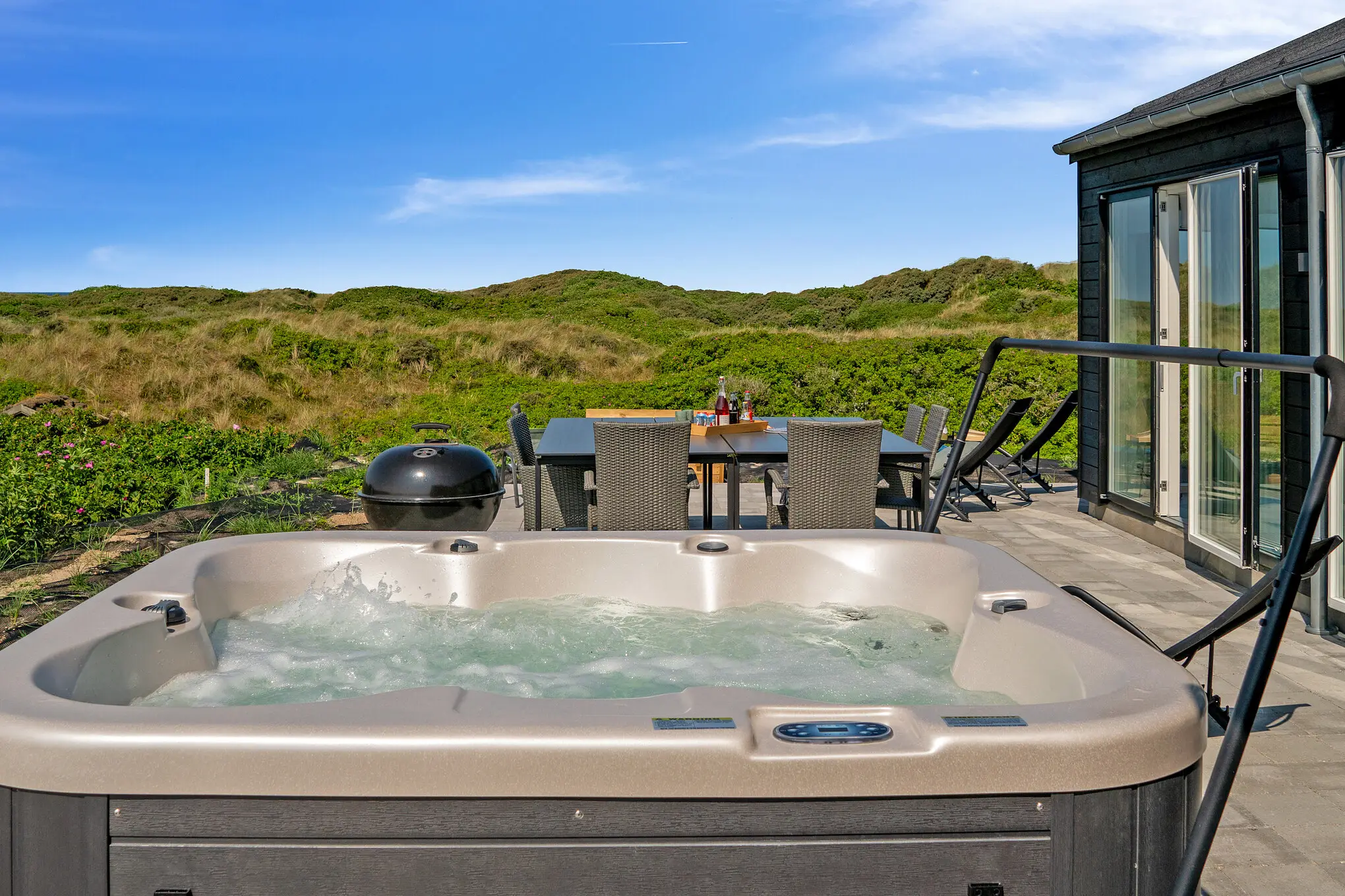 Udendørs spa på terrasse ved sommerhus med udsigt over klitlandskab