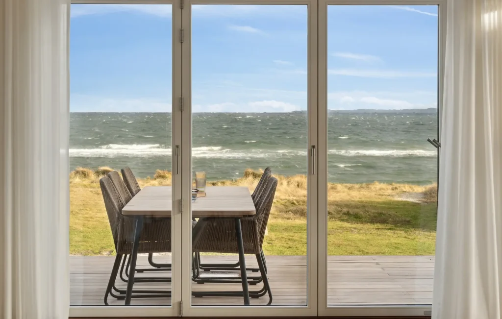sommerhus ved stranden med havebord, stole og udsigt til hav og strand