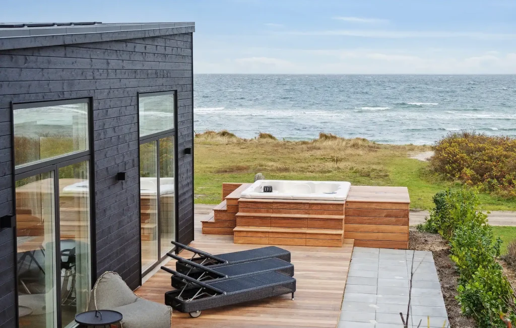 sommerhus ved vandet med solsenge, spabad og udsigt til vandet