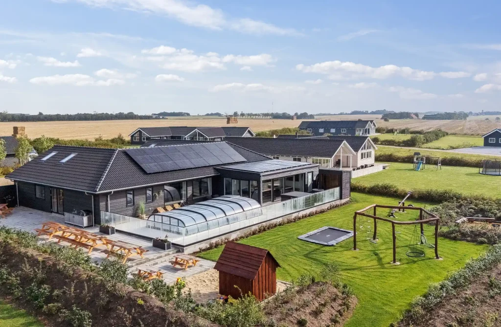 stort sommerhus med pool udendørs og have med trampolin og legeplads