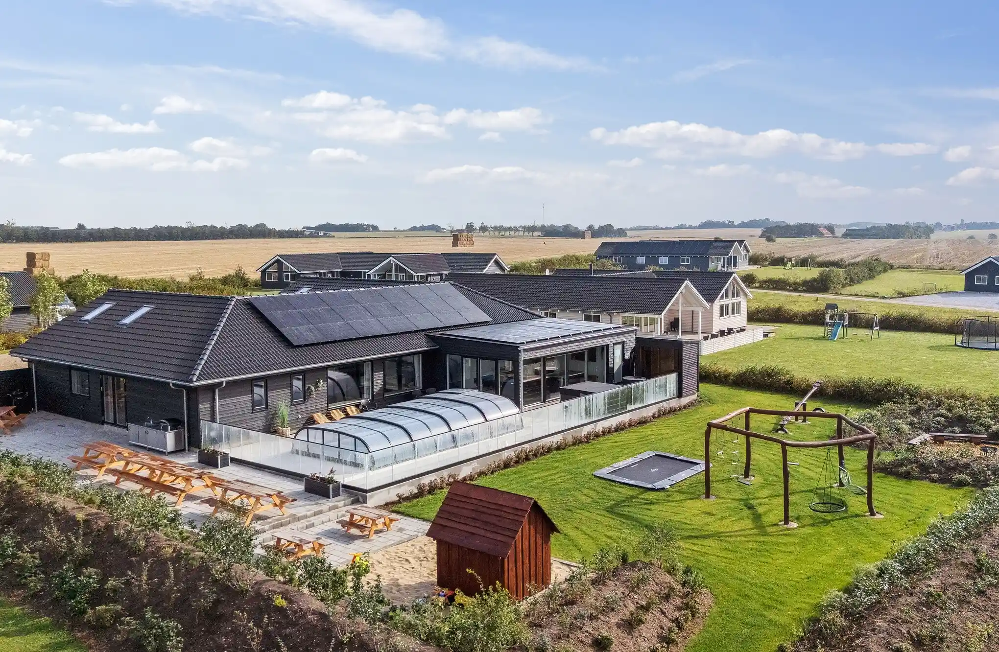Stort sommerhus med udendørs pool, have med trampolin og legeplads.
